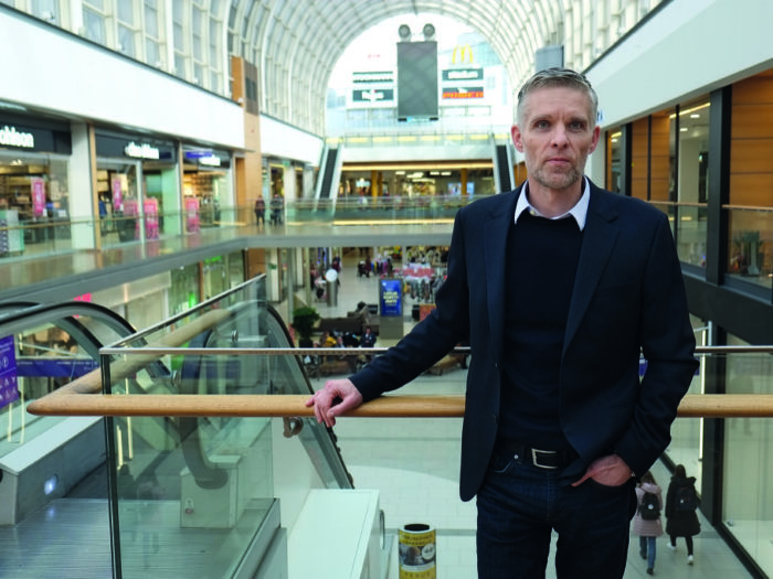 Man står vid rulltrappa. Bakom honom ser man köpcentret Itis långa korridor.